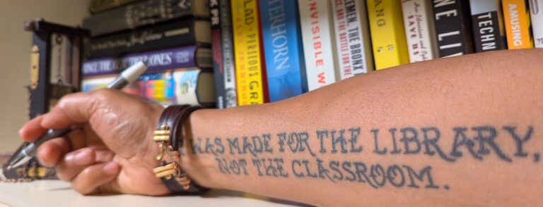 An arm with a tattoo: "I was made for the library, not the classroom."